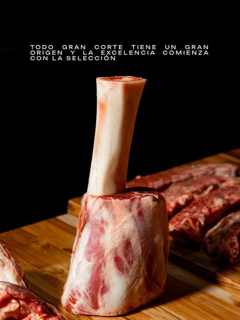 Corte de carne crudo con hueso sobre una tabla, con más cortes al fondo