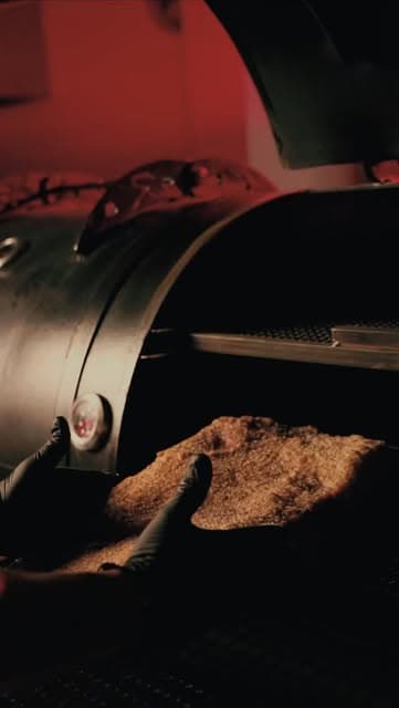 Ahumador metálico abierto con un brisket enrubado bajo luz roja