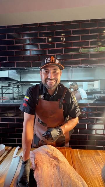 Chef sonriendo con un brisket crudo en la cocina