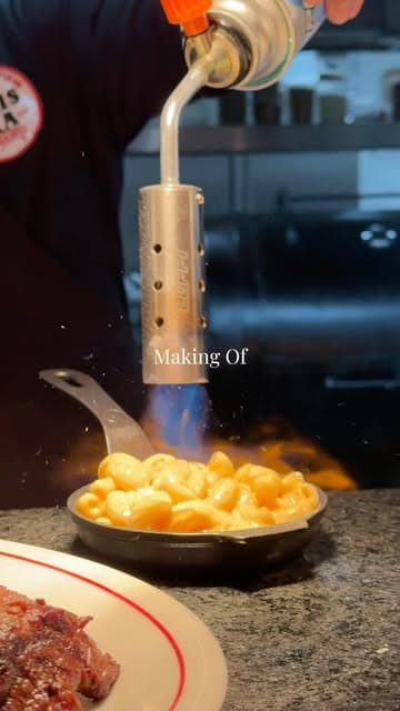 Soplete flameando mac and cheese en una sartén de hierro